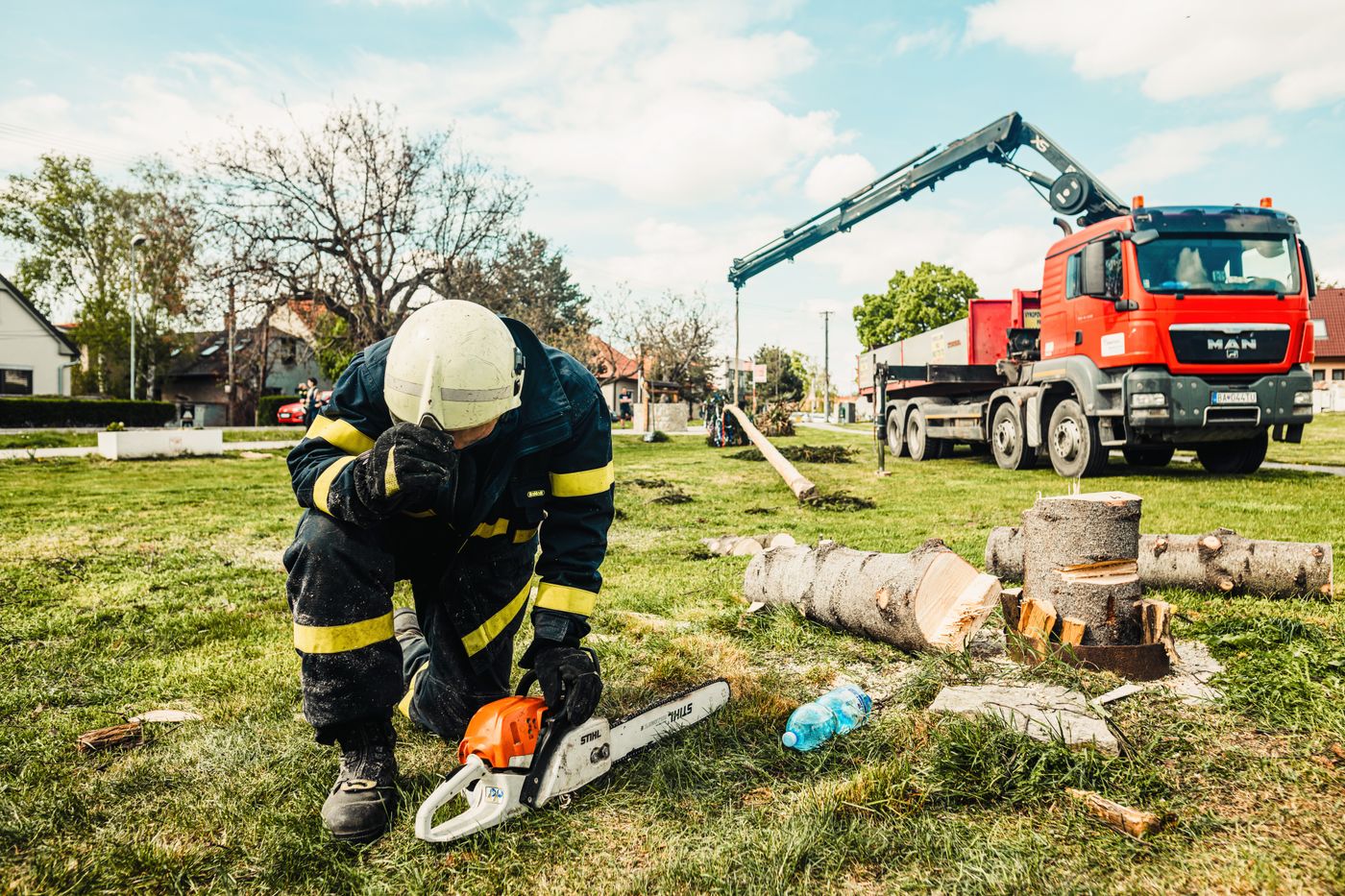 Tree-care crew preparing equipment beside cleared timber